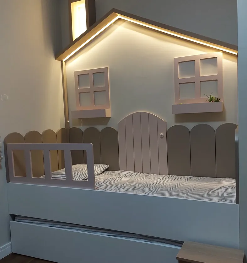 Quarto infantil com cama em formato de casinha, cerquinha, janelas decorativas, iluminação embutida no telhado e cama auxiliar